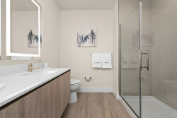Unwind in this stylish bathroom, filled with natural light, featuring a spacious glass shower and a sleek white vanity paired with warm wood tones, offering a perfect retreat for relaxation after your adventures.