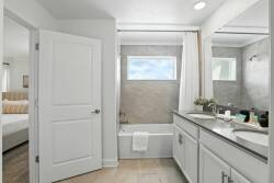 This bright, airy bathroom boasts a sleek dual-sink vanity with ample storage and a calming gray tile backdrop. With natural light streaming in, it creates a clean, modern atmosphere perfect for unwinding.