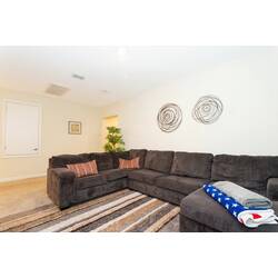 Relax in a cozy upstairs living area with a large sectional sofa, soft carpet, striped rug, wall decor, warm lighting, decorative pillows, and a comfortable space for family downtime.