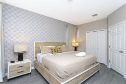 Enjoy a beautifully decorated bedroom with a plush king-sized bed, vibrant pillows, stylish nightstands, and warm lighting, all enhanced by elegant geometric wallpaper for a cozy and inviting atmosphere during your stay.