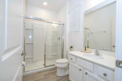This bright and airy bathroom boasts sleek glass shower doors and a spacious vanity with white cabinetry, creating a clean, fresh atmosphere that enhances your daily routines and offers a perfect blend of style and functionality.