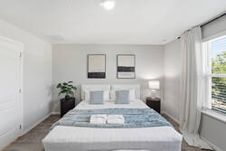 Rest in a bright bedroom with a cozy white bed, soft blue accents, fresh greenery, natural light, and simple décor, creating a calm and comfortable space for your vacation.