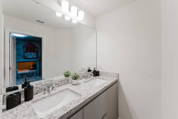 Enjoy a modern bathroom featuring elegant granite countertops and dual sinks, perfect for a refreshing start. The minimalist decor and stylish lighting foster a clean, spacious ambiance, inviting you to relax and unwind.