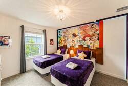 Rest in a playful Toy Story themed bedroom with two cozy beds, purple blankets, character wall art, soft lighting, and a bright window, creating a fun space for kids during vacation.