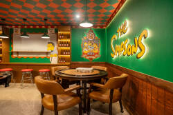 Enter a vibrant game room with green walls showcasing iconic "The Simpsons" art. Cozy leather seating surrounds a round table, making it the perfect venue for fun gatherings and friendly competition. Enjoy your time here!