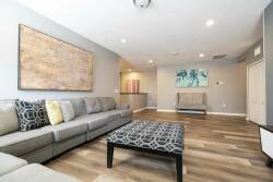 Relax in a stylish living area with a spacious gray sectional and a chic patterned coffee table. Enjoy the soft lighting and neutral tones that create a serene atmosphere, ideal for unwinding after your day of exploration.
