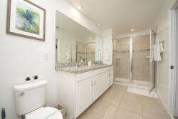 Step into this bright bathroom featuring sleek granite countertops and ample mirrored space that enhances the light. The walk-in shower offers a refreshing modern touch, while subtle decor adds a hint of tranquility to your stay.