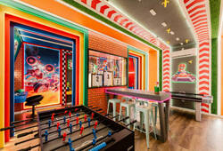 Discover a lively game room adorned with colorful decor, featuring a foosball table and stylish bar-height seating. Enjoy the vibrant hues and dynamic artwork, setting the perfect atmosphere for memorable, fun-filled evenings.