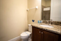 This bathroom boasts a sleek granite countertop and warm wood cabinetry, with natural light enhancing the bright atmosphere. You'll appreciate the convenience of well-placed toiletries, making your stay even more enjoyable.