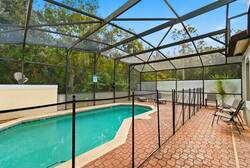 Step outside to the screened pool area with a textured brick patio and sparkling water. Relax in comfortable lounge chairs amidst lush greenery, providing a refreshing escape just steps from your door.
