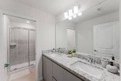 Experience bathroom comfort with a spacious double vanity featuring granite countertops and modern fixtures. The sleek glass shower beckons relaxation, while soft lighting adds a soothing touch to your experience.