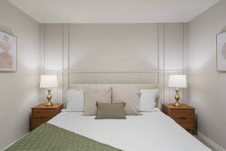 Relax in a cozy neutral bedroom with a comfortable bed, soft curtains, warm bedside lamps, wood nightstands, and simple decor, creating a peaceful space for vacation rest.