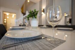 Enjoy a delightful dining experience in a chic setting where modern design meets comfort. Elegant glassware and textured placemats enhance the bright ambiance of soft lighting, ensuring every meal is truly memorable.