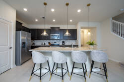 Indulge in culinary delights in this chic kitchen, boasting sleek dark cabinets and elegant pendant lighting. The spacious island with plush barstools offers an ideal spot for casual dining and engaging conversation.