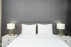 Enjoy restful nights in this stylish bedroom with a deep gray textured wall and soft white linens. Elegant bedside lamps enhance the cozy, welcoming atmosphere for a perfect retreat.