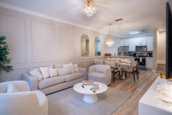 Enjoy a cozy living area with soft beige furnishings and a plush rug, perfect for relaxation. The elegant chandelier adds warmth to the dining space, seamlessly connecting to the modern kitchen for effortless entertaining.