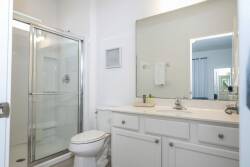 Relax in this bright bathroom with a spacious glass shower and sleek white cabinetry, creating a fresh atmosphere. Natural light streams in, enhancing the airy feel and making it the perfect space to unwind and refresh.