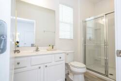 This bright, airy bathroom features a clean white vanity and modern fixtures for a refreshing vibe. Enjoy the spacious walk-in shower with glass doors and let natural light create a serene atmosphere perfect for relaxation.