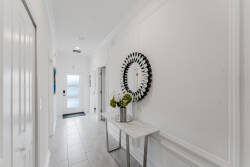 Step into this bright hallway with sleek light gray tiles that create a welcoming atmosphere. A chic round mirror reflects natural light, while a stylish console table adds sophistication for your vacation essentials.
