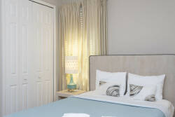 Bathe in natural light as it streams through soft curtains, illuminating the cozy bedroom adorned with a plush headboard and fresh bedding. A stylish nightstand adds a touch of charm, inviting relaxation in this restful haven.
