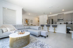 Bright and airy, this living space combines comfort and style with a plush gray sectional and a chic gold coffee table. The sleek kitchen, featuring stainless steel appliances, invites you to embark on culinary adventures.
