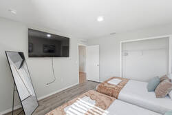 Rest in a bright bedroom with two cozy beds, soft pillows, warm blankets, abstract wall art, natural light, and clean neutral tones, creating a comfortable space for your vacation.