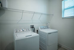 Experience a bright and airy laundry room with natural light streaming in. The sleek white appliances and practical shelving above keep everything organized, ensuring your stay is both enjoyable and stress-free.