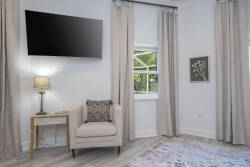 Enjoy the gentle light streaming through the large window, highlighting a cozy corner with a plush armchair and soft throw pillows. The pastel decor and elegant curtains create a soothing atmosphere perfect for relaxation.