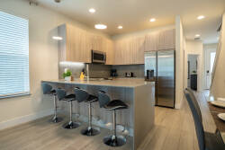 This kitchen features modern cabinetry and a spacious island perfect for casual meals or morning coffee, while the soft light from the large window enhances the inviting atmosphere for your culinary adventures.