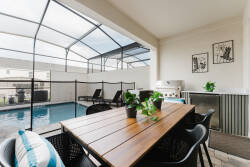 Relax and savor al fresco dining in our charming outdoor area, complete with a sturdy wooden table and sleek black chairs. The screened enclosure invites natural light, while lush plants enhance the refreshing ambiance for your.