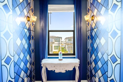Enter a vibrant space with bold blue geometric patterns that create a playful vibe. The elegant white console table and warm lighting add charm, while a large window lets in natural light and offers a peek outside.