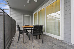 Enjoy outdoor dining in a covered screened patio with a table, black chairs, ceiling fan, sliding glass doors, pool views, and nearby lounge chairs, creating a comfortable space for vacation meals.
