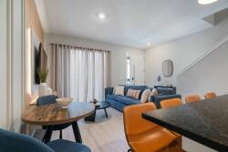 Relax in a cozy living area featuring a plush blue sofa and warm wood accents. Natural light streams in through large curtains, creating a cheerful atmosphere perfect for unwinding after a day of exploration.