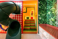 Step into a vibrant play area where colorful walls and a playful slide invite fun and adventure. The whimsical decor, with lush greenery and bold patterns, creates an inspiring backdrop for unforgettable experiences.