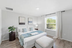 Rest in a bright and peaceful bedroom with a cozy white bed, soft blue accents, fresh greenery, wood floors, natural light, and simple décor, creating a comfortable retreat for your vacation.