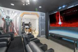 Experience cinematic magic in our uniquely designed home theater featuring plush black leather seating and themed wall art. Enjoy a large screen for your favorite films, making every movie night truly unforgettable.