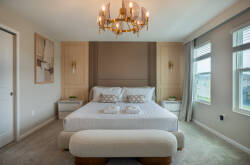 Enjoy comfort in this stylish bedroom with a plush king-sized bed, elegant nightstands, and soothing neutral tones. Large windows and a beautiful chandelier enhance the airy ambiance for a relaxing stay.