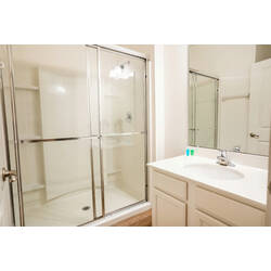 Enjoy a bright and clean bathroom with a glass-enclosed shower, spacious vanity, and large mirror. Neutral tones, soft lighting, and a simple layout create a fresh and comfortable space to relax during your vacation.