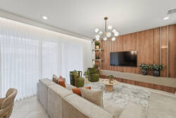 Relax in a stylish living room with a cozy sectional, green accent chairs, wall-mounted TV, warm wood feature wall, soft white curtains, modern lighting, and elegant decor for vacation moments.