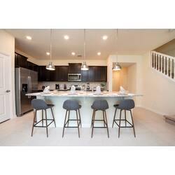 Gather in a bright kitchen with dark cabinets, stainless steel appliances, granite island, pendant lights, bar seating, and place settings ready for vacation meals