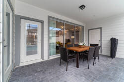 Step outside to enjoy al fresco dining on a stylish wooden table, surrounded by sleek black chairs. The expansive glass doors invite natural light, seamlessly blending indoor comfort with outdoor charm in this inviting space.