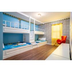 This cheerful bunk room features cozy twin beds with vibrant blue bedding, creating a fun atmosphere. Natural light streams in through a large window, enhancing the playful decor and sleek wooden flooring for a bright, inviting.