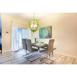Enjoy meals in this bright dining area featuring modern chairs and a stylish wooden table. The artistic wall decor and warm light fixture add charm, while natural light fills the space through the sliding glass doors.