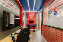 Welcome to our vibrant gaming room, where bold red accents and playful decor create an energizing atmosphere. With sleek gaming chairs and a large screen, this space guarantees hours of fun and entertainment for all guests.