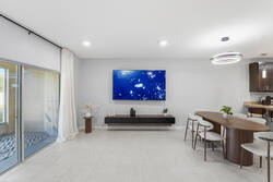 Gather in a bright open living and dining area with a cozy sectional sofa, wood dining table, modern lighting, greenery, and a nearby kitchen, creating a comfortable space for your vacation.