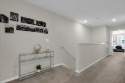 Enter a beautifully designed hallway with warm beige walls and soft carpet. A stylish console table displays tasteful decor, complemented by striking black-and-white artwork, inviting you to explore further.