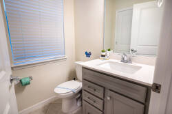 Bright and functional, this bathroom features a sleek vanity with a polished countertop and ample storage. Natural light streams in through the window, illuminating the clean lines and subtle decor for a refreshing atmosphere.