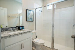 This bright bathroom features a sleek glass shower, perfect for refreshing after your adventures. The elegant gray countertop pairs beautifully with the white cabinetry, and natural light creates a serene atmosphere for your stay.