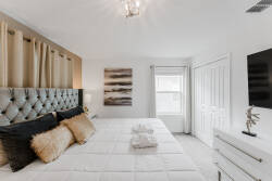 This elegantly designed bedroom features a plush tufted headboard and soft pillows, creating a cozy retreat. Natural light enhances the neutral tones and chic decor, offering a serene sanctuary for your stay.