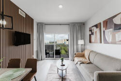 Enjoy the natural light streaming through the large glass door, enhancing the sleek sofa and elegant wood accents. The modern decor and neutral tones create a cozy, sophisticated atmosphere ideal for your relaxation.
